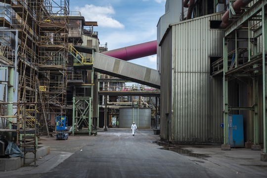 Een man in witte overall wandelt door de zinkfabriek van Nyrstar in Balen.