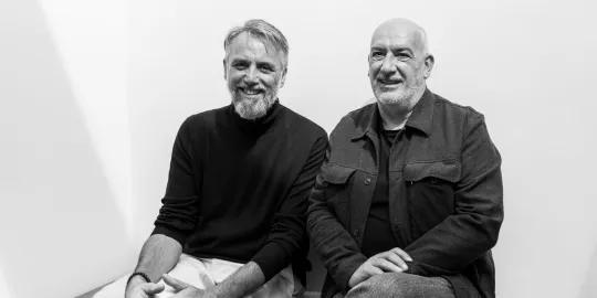 Zwartwitfoto van Sven Tuytens en Vincent Scheltiens die naast elkaar zitten. 