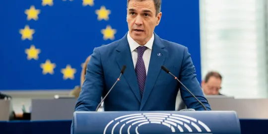 Pedro Sánchez in blauw maatpak op het spreekgestoelte van het Europees Parlement. 