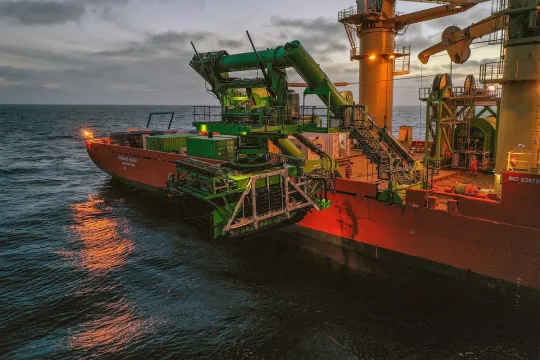 Een mijnexploratieschip lanceert een onderwatervoertuig dat is uitgerust om sediment van de zeebodem te verzamelen. 