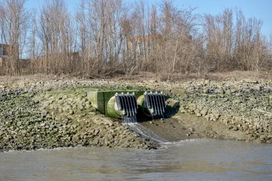 Langs een grote leiding stroomt water de Schelde binnen.