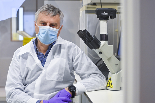 Viroloog Johan Neyts naast een microscoop in zijn laboratorium.