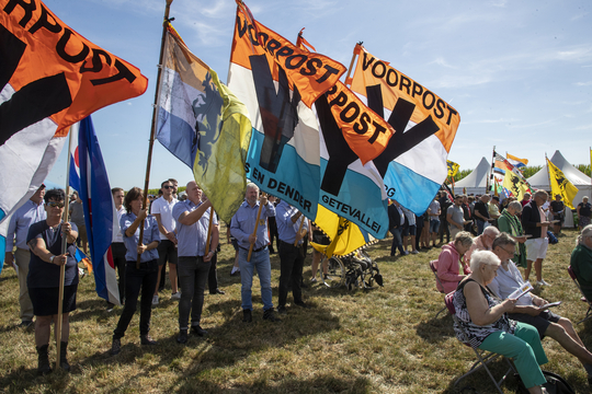 Militanten van Voorpost zwaaien met vlaggen op de IJzerwake in 2022.