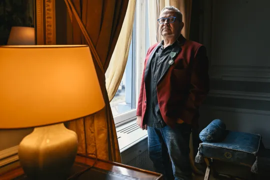 Tom Lanoye poseert op de Franse ambassade in Brussel met zijn ereteken als Chevalier de l'ordre français des Arts et des Lettres.