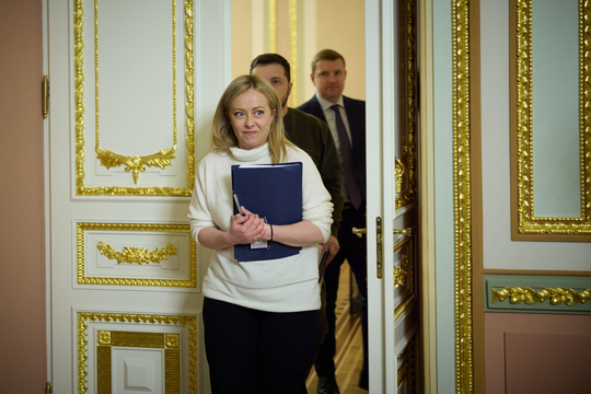 Italiaans premier Giorgia Meloni verlaat via een met bladgoud omlijste deur een kamer in Kiev bij een bezoek aan de Oekraïense president Volodimir Zelenski, die achter haar loopt.