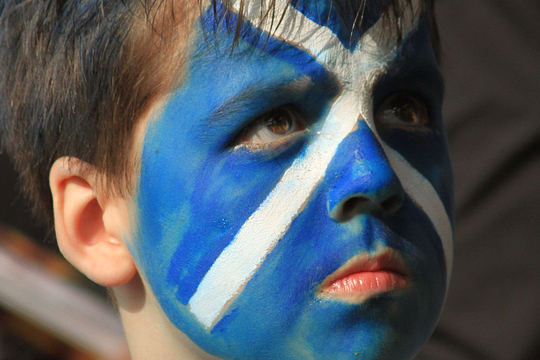 Een kind met op zijn gezicht een Schotse vlag geschminkt