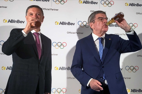 CEO van AB Inbev Michael Doukeris (links) en IOC-voorzitter Thomas Bach drinken een biertje tijdens de persconferentie om aan te kondigen dat AB InBev sponsor wordt van de Olympische Spelen.