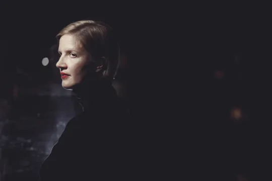 Portretfoto van Julie Cafmeyer. Ze staat in de schaduw en enkel haar gezicht is belicht.