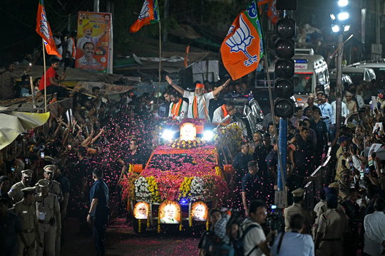 Indiaas premier Narendra Modi (BJP) staat met opengesperde armen op een uitbundig versierde truck tijdens een verkiezingsrally in Hyderabad.