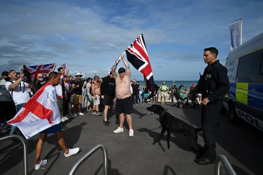 Extreemrechtse activisten zwaaien met vlaggen bij een schip waar asielzoekers gehuisvest worden in Weymouth, in het zuidwesten van het Verenigd Koninkrijk.