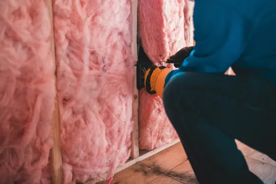 Een persoon plaatst isolatiemateriaal in een huis.