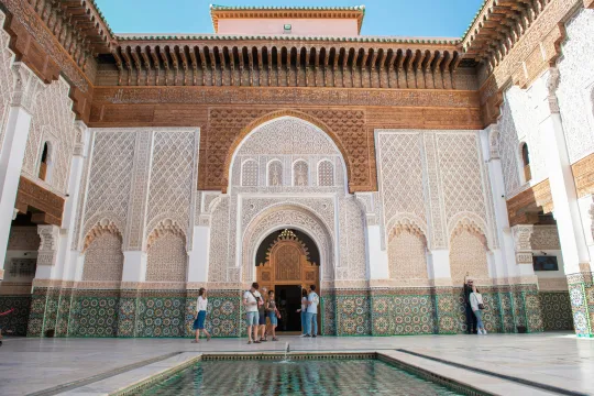 Mensen bezoeken de binnenplaats van de Ben Joesoefmadrassa in Marrakesh.