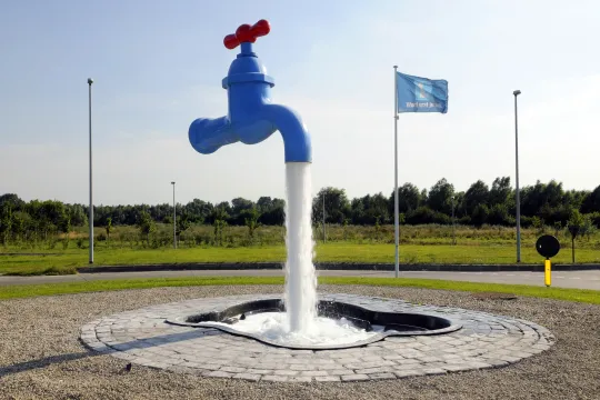Kunstwerk van een grote blauwe waterkraan die lijkt te zweven.