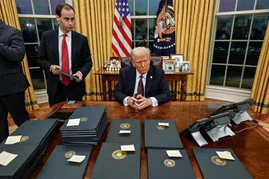 Amerikaans president Donald Trump zit aan zijn bureau in The Oval Office op 20 januari 2025, voor hem liggen verschillende presidentiële decreten.