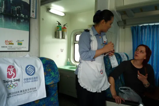 Jeanne Boden in gesprek met een bediende op de trein ten tijde van de Olympische Spelen in Peking.