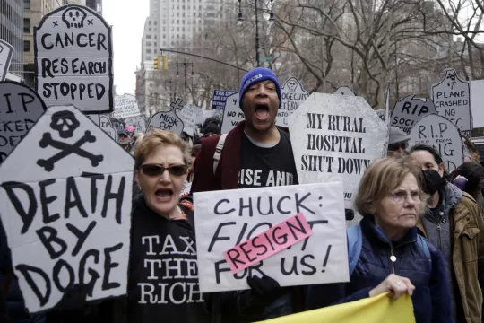Betogers houden slogans in de lucht tegen Donald Trumps beleid tijdens de ‘March to Stop the Cuts’ in New York op 15 maart.