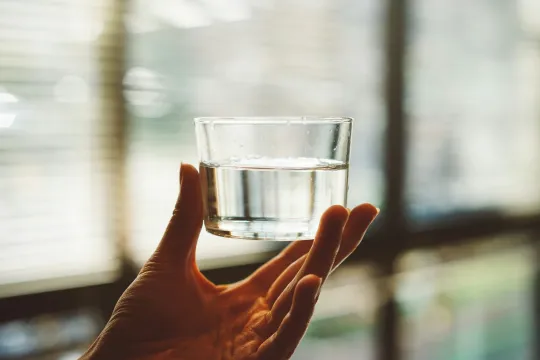 Een hand houdt een bakje water vast