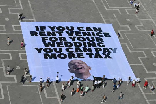 Actievoerders van Greenpeace protesteren met een gigantische banner tegen het huwelijksfestijn van Jef Bezos.