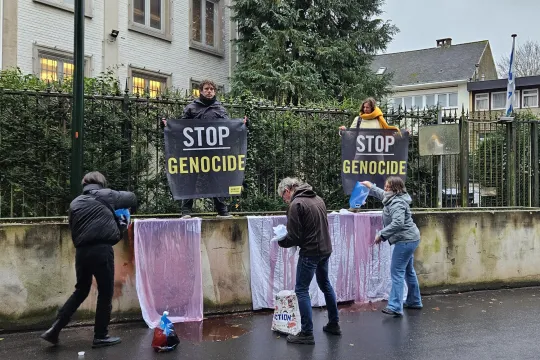 Amnesty International voerde afgelopen december actie tegen de genocide in Gaza, aan de Israëlische ambassade in Brussel. Twee personen houden doeken op met de 'Stop genocide', drie anderen zijn in de weer met rode verf.