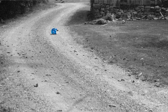 Zwartwit beeld van een weg, met op de grond één blikje, uitgelicht in het blauw. 