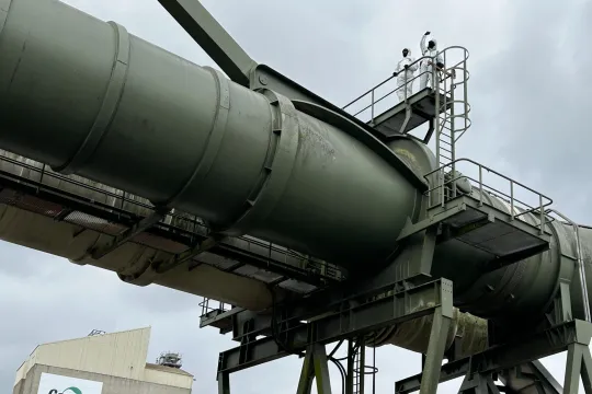 Twee actievoerders van Code Rood in witte verfpakken staan bovenop een hoge en gigantische pijpleiding van de Cargill-fabriek in Gent.
