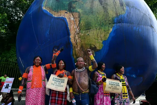 Inheemse personen poseren naast een gigantische opblaasbare wereldbol tijdens de “Indigenous People Global March” op de COP30 VN-klimaatconferentie in Belém, in de staat Pará, Brazilië, op 17 november 2025. 