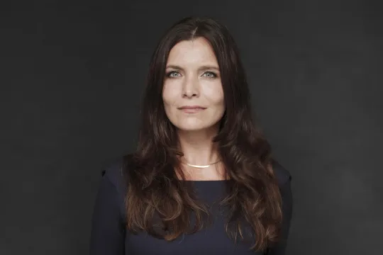 Portret van Rosan Smits tegen een zwarte achtergrond. 
