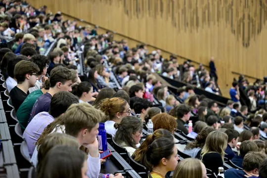 Studenten luisteren aandachtig in een volle aula op de campus van UGent