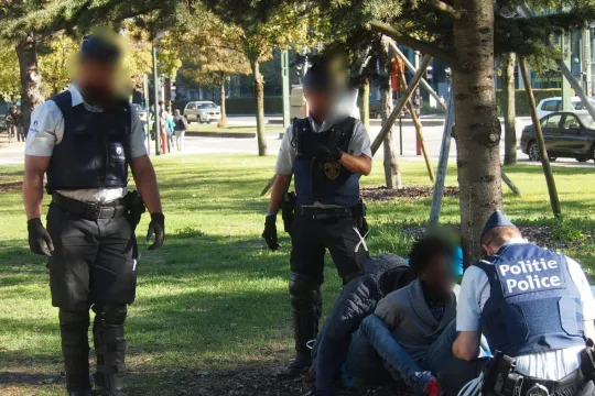 Drie politieagenten arresteren personen zonder verblijfsvergunning. 