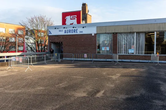 Een gemeentelijke feestzaal op het dak van de Delhaize, met een rij dranghekken op de parking ervoor.
