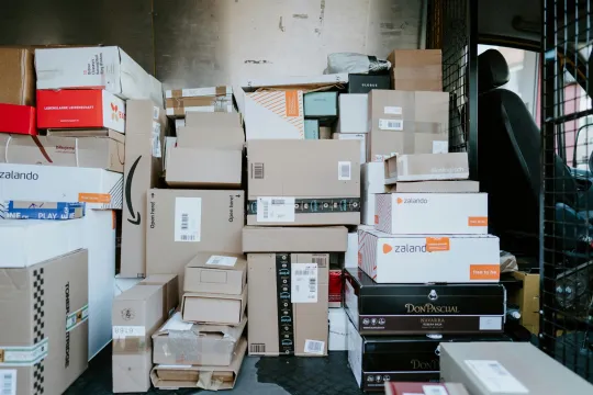 Binnenkant van een bestelwagen die volgeladen is met postpakjes van onder andere Zalando en Amazon. 