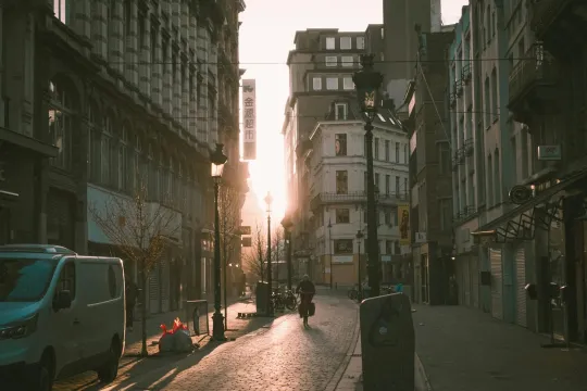 Een vrouw fietst bij valavond door een lege Brusselse staat. 