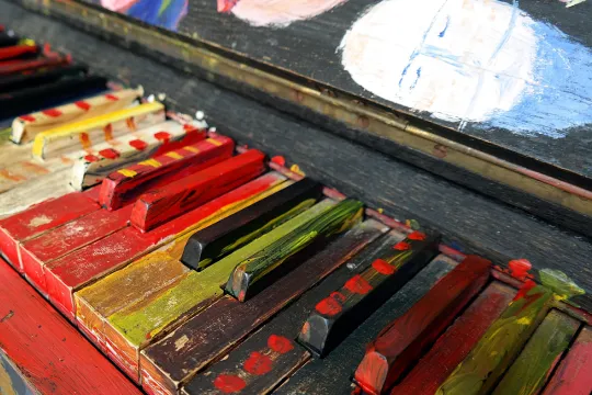 Close-up van een piano waarvan de toetsen in verschillende levendige kleuren geschilderd zijn. 