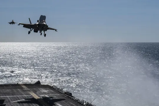Een F35 landt op een platform in de zee. 
