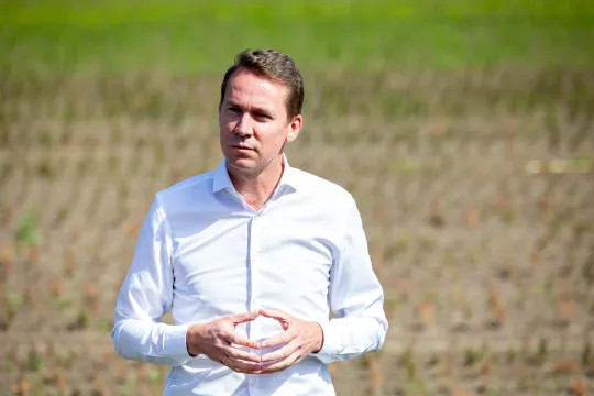 Jo Brouns staat, gekleed in een wit hemd, op een veld.