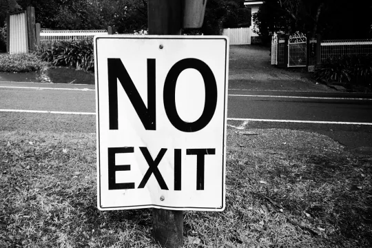 Zwartwit beeld van een bordje met de woorden 'No exit' in een woonwijk.