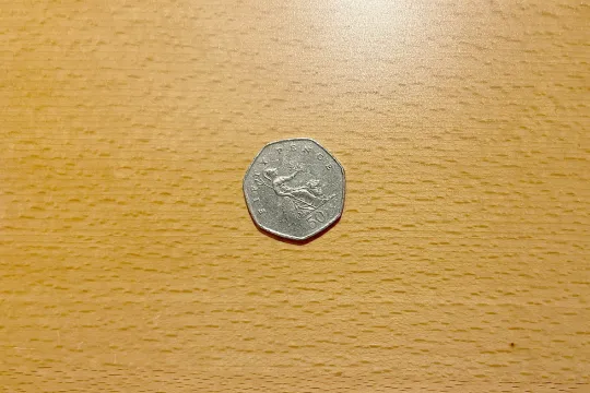 Een muntstuk van vijtig pence op een egalen houten ondergrond. 
