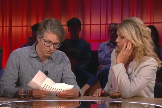 Maarten Boudry leest een papier in De Afspraak, naast hem zit Goedele Liekens. 