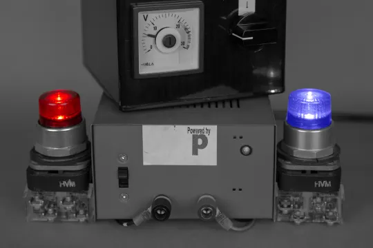 Een machine is verbonden aan twee lampen. De linkse is rood, de rechtse is blauw. 