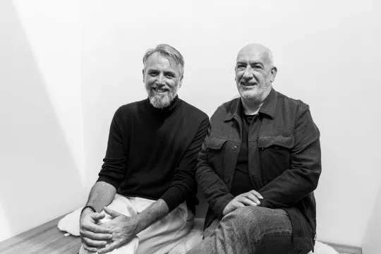 Zwartwitfoto van Sven Tuytens en Vincent Scheltiens die naast elkaar zitten. 