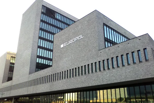 Vooraanzicht van een groot grijzen gebouw, dat de kantoren van Europol huisvest.