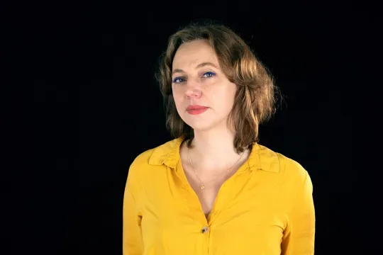 Een portretfoto van Lisa Doeland, tegen een zwarte achtergrond. 