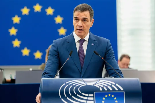 Pedro Sánchez in blauw maatpak op het spreekgestoelte van het Europees Parlement. 