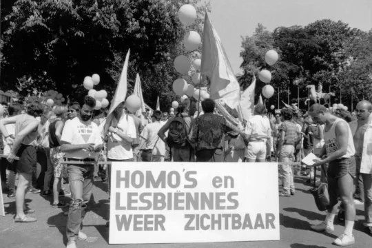 zwart-witfoto van een demonstratie met groot wit spanbord "homo's en lesbiennes weer zichtbaar"