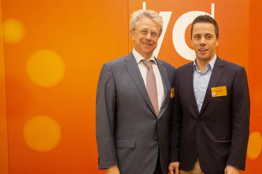 Johan en Tom Willemen van de gelijknamige bouwgroep, beiden in kostuum, op de nieuwjaarsreceptie (2018) van VOKA, tegen een oranje achtergrond.