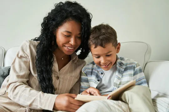 Vrouw en een jong kind lezen samen een boek in een zetel.