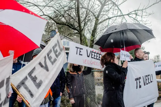actievoerders houden borden en spandoeken vast met de woorden 'te veel'