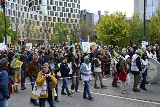 Klimaatbetogers van verschillende organisaties lopen door een hoofdstraat in Brussel.