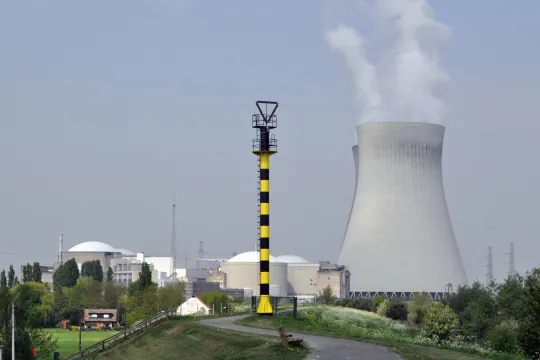 Een fiets weg op een heuvel kronkelt naar gebouwen van een kerncentrale in Doel. 