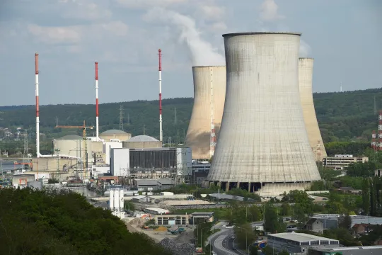 Drie grote dampende kerncentrales in een industrieel landschap. 